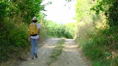 Kırsal alanlarda yürüyüş yapan bir kadın, açık araziler, temiz hava ve huzurlu kırsal manzarayla çevrili. Açık havanın doğal güzelliğini ve sükunetini seviyor..