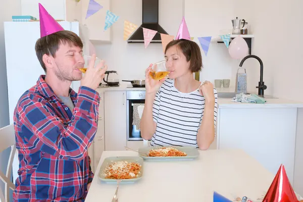 Genç çift sıcak bir ortamda pasta ve kahkahaların tadını çıkararak evde rahat bir doğum günü kutluyor. Aile makarna yiyor ve şarap içiyor. Kutlamak için, afiyet olsun ve şerefe.