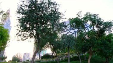 Dubai 'de Al Seef Parkı' nı gezen etnik giysili ve şapkalı genç bir kadın. Geleneksel Emirati mimarisi ve modern atmosferiyle çevrelenmiş Dubai Deresi 'nin kültürel mirasının cazibesine sahip..