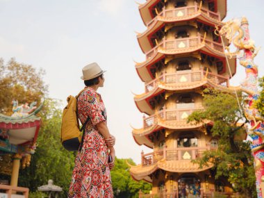 Bangkok 'taki Budist Tapınakları' nın yakınlarındaki Renkli Sokakları Keşfeden Kadın. Bangkok 'un canlı sokaklarında yürüyen genç bir gezgin, karmaşık tapınak detaylarına ve canlı çevresine hayran...