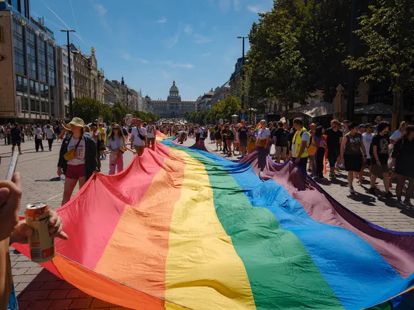 Prag, Çek Cumhuriyeti - 12 Ağustos 2023: Prag Onur Festivali Geçidi. Prag Gay Onur Yürüyüşü 'nde elinde kocaman bir gökkuşağı bayrağı olan insanlar. Wenceslas Meydanı 'nda Ulusal Müze önünde kalabalık var..