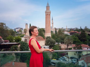 Sıcak yaz akşamları Antalya 'nın dar sokaklarında kırmızı elbiseli bir kadın yürüyor. Tarihsel atmosfer ve Akdeniz cazibesi barışçıl seyahat deneyimleri yaratır. Kalechi manzarası