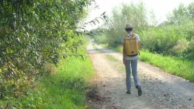 Kırsal alanlarda yürüyüş yapan bir kadın, açık araziler, temiz hava ve huzurlu kırsal manzarayla çevrili. Açık havanın doğal güzelliğini ve sükunetini seviyor..