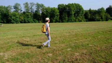 Kırsal alanlarda yürüyüş yapan bir kadın, açık araziler, temiz hava ve huzurlu kırsal manzarayla çevrili. Açık havanın doğal güzelliğini ve sükunetini seviyor..