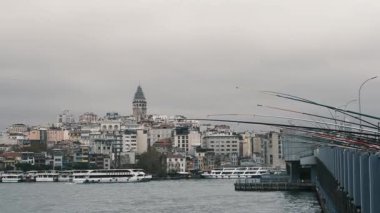 İstanbul, Türkiye - 3 Aralık 2023. Galata Köprüsü 'nde oltaları olan balıkçılar. Tarihi ve modern şehrin arka planına çubuklarla bakan balıkçıların manzara görüntüsü.