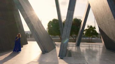 Abu Dabi 'deki Şeyh Zayed Büyük Camii yakınlarındaki Wahat Al Karama' daki geleneksel Arap elbiseli kadın, gün batımında kültürel zarafet ve ikonik İslami mimari sergiliyor..