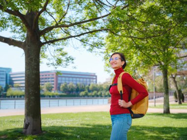 Turist kadın modern Frankfurt 'u keşfediyor, çağdaş mimari, gökdelenler ve kentsel alanlarla hareketli caddelerde yürüyor, modern yan tarafların canlı atmosferinin tadını çıkarıyor..