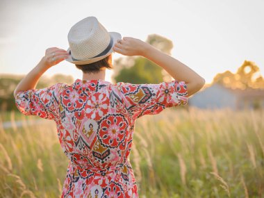 Yaz sonlarında Avrupa 'nın pitoresk alanlarında yürüyen genç bir kadın. Altın güneş ışığı, yemyeşil yemyeşil ve sakin kırsal atmosfer huzurlu bir kırsal alan yaratır..