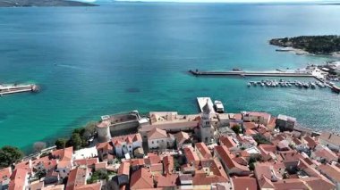 Krk Adası 'ndaki tarihi kıyı kasabası, dolambaçlı caddelerde, marinada ve şehir duvarlarında güneş ışığının Adriyatik Denizi' ne yansıdığı eski taş evler. Nefes kesici hava manzarası,