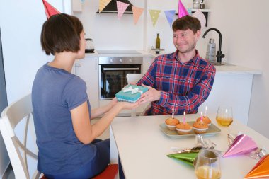 Aile, doğum günü kutlaması için güzel dekore edilmiş yemek odasında hediyelerini değiş tokuş eder. Dekorasyon şenlikli dekorasyonlar ve sıcak, neşeli atmosferle dolu..