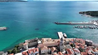 Krk Adası 'ndaki tarihi kıyı kasabası, dolambaçlı caddelerde, marinada ve şehir duvarlarında güneş ışığının Adriyatik Denizi' ne yansıdığı eski taş evler. Nefes kesici hava manzarası,