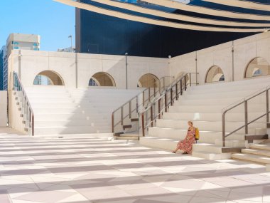 Abu Dabi 'de Qasr Al Hosn Parkı' nı keşfeden genç bir kadın. Yeşillik ve tarihi simgelerle çevrelenmiş, kentin kalbindeki sakin atmosfer ve Emirati mirasının tadını çıkarıyor..