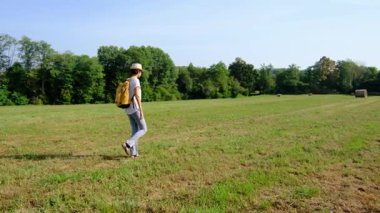 Kırsal alanlarda yürüyüş yapan bir kadın, açık araziler, temiz hava ve huzurlu kırsal manzarayla çevrili. Açık havanın doğal güzelliğini ve sükunetini seviyor..