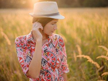Yaz sonlarında Avrupa 'nın pitoresk alanlarında yürüyen genç bir kadın. Altın güneş ışığı, yemyeşil yemyeşil ve sakin kırsal atmosfer huzurlu bir kırsal alan yaratır..