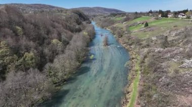 Korana Nehri 'nin insansız hava aracı manzarası Slunj yakınlarındaki engebeli arazide dönüyor. Ağaçlar kıştan dolayı hala çıplakken, berrak su ve yosunlu bankalar yaklaşan baharı ima ediyorlar. Hırvat doğası.
