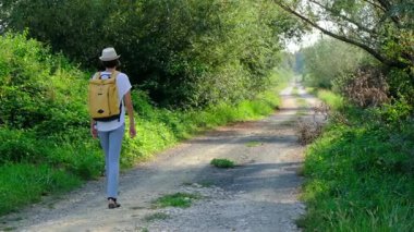 Kırsal alanlarda yürüyüş yapan bir kadın, açık araziler, temiz hava ve huzurlu kırsal manzarayla çevrili. Açık havanın doğal güzelliğini ve sükunetini seviyor..