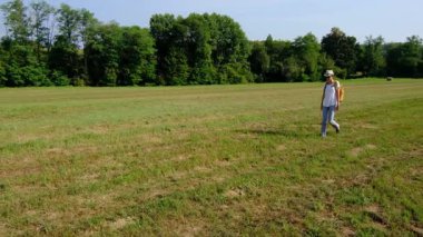 Kırsal alanlarda yürüyüş yapan bir kadın, açık araziler, temiz hava ve huzurlu kırsal manzarayla çevrili. Açık havanın doğal güzelliğini ve sükunetini seviyor..