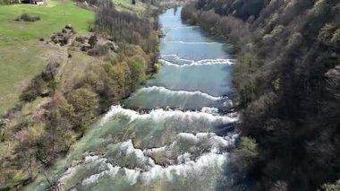 Korana Nehri 'nin insansız hava aracı manzarası Slunj yakınlarındaki engebeli arazide dönüyor. Ağaçlar kıştan dolayı hala çıplakken, berrak su ve yosunlu bankalar yaklaşan baharı ima ediyorlar. Hırvat doğası.