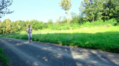 Tarlalar ve ormanlarla çevrili kırsal toprak yolda yürüyen bir adam kırsal hayatın huzurlu ve kırsal atmosferini yakalıyor. Yalnızlığı ve doğayı vurgulayan basit, sessiz bir sahne..