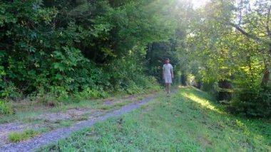 Tarlalar ve ormanlarla çevrili kırsal toprak yolda yürüyen bir adam kırsal hayatın huzurlu ve kırsal atmosferini yakalıyor. Yalnızlığı ve doğayı vurgulayan basit, sessiz bir sahne..