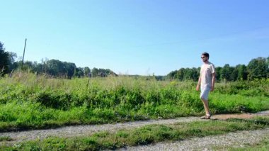 Tarlalar ve ormanlarla çevrili kırsal toprak yolda yürüyen bir adam kırsal hayatın huzurlu ve kırsal atmosferini yakalıyor. Yalnızlığı ve doğayı vurgulayan basit, sessiz bir sahne..