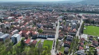 Slovenya, Maribor 'un güneşli bahar günündeki hava görüntüleri. Çatılar, şehir sokakları, tarihi binalar çiçek açan ağaçlar ve yeşil alanlarla çevrili, mükemmel bir kültür ve doğa karışımı sunuyorlar.