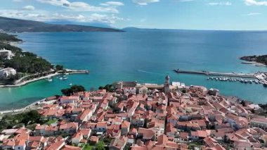 Krk Adası 'ndaki tarihi kıyı kasabası, dolambaçlı caddelerde, marinada ve şehir duvarlarında güneş ışığının Adriyatik Denizi' ne yansıdığı eski taş evler. Nefes kesici hava manzarası,