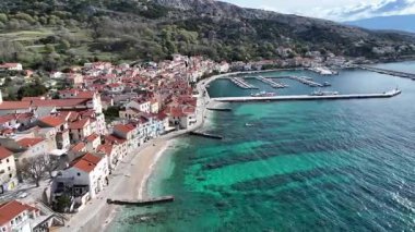 Baska plajı ve kristal berraklığında turkuaz su, marina botları, şehir sokağı, Krk Adası 'ndaki insansız hava aracından yakalanan güneşli yaz havası. Adriyatik Denizi 'ndeki Baska Tatil Kasabası