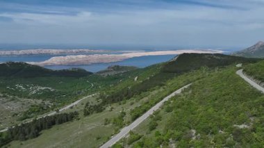 İlkbaharda Velebit dağ sırasından geçen manzara, bahar güneşinde yeşil Velebit dağlarından geçen yol, Hırvatların doğal manzarasını ve huzurlu uzak arazisini gösteriyor