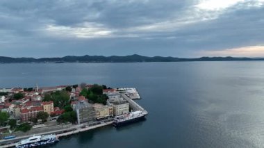 Zadar marinası ve yukarıdan görünen antik kasaba. Kıyı ilkbahar atmosferindeki Zadars rıhtımı, kırmızı çatılar, marina ve Roma mirasının güneşli hava görüntüleri