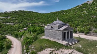 Tulove Grede dağları yakınlarındaki St. Francis kilisesinin insansız hava aracı görüntüsü. Tulove Grede Dağı 'nın yanındaki küçük taş kilise, uzak Hırvat manzarasındaki yaban tepeleri ve bahar bitkileri tarafından çerçevelenmiş yukarıdan görülüyor.