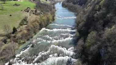 Korana Nehri 'nin insansız hava aracı manzarası Slunj yakınlarındaki engebeli arazide dönüyor. Ağaçlar kıştan dolayı hala çıplakken, berrak su ve yosunlu bankalar yaklaşan baharı ima ediyorlar. Hırvat doğası.