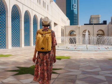 Abu Dabi 'de Qasr Al Hosn Parkı' nı keşfeden genç bir kadın. Yeşillik ve tarihi simgelerle çevrelenmiş, kentin kalbindeki sakin atmosfer ve Emirati mirasının tadını çıkarıyor..