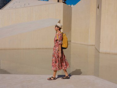 Abu Dabi 'de Qasr Al Hosn Parkı' nı keşfeden genç bir kadın. Yeşillik ve tarihi simgelerle çevrelenmiş, kentin kalbindeki sakin atmosfer ve Emirati mirasının tadını çıkarıyor..