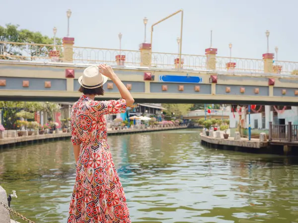 Malacca, Malezya 'nın canlı sokaklarını keşfeden etnik giysili ve şapkalı genç bir kadın. Kültürel miras, renkli mimari ve tropikal cazibenin bir karışımı. Mükemmel seyahat ve yaşam tarzı anları.