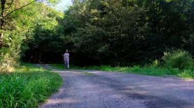 Tarlalar ve ormanlarla çevrili kırsal toprak yolda yürüyen bir adam kırsal hayatın huzurlu ve kırsal atmosferini yakalıyor. Yalnızlığı ve doğayı vurgulayan basit, sessiz bir sahne..