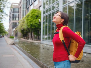 Turist kadın modern Frankfurt 'u keşfediyor, çağdaş mimari, gökdelenler ve kentsel alanlarla hareketli caddelerde yürüyor, modern yan tarafların canlı atmosferinin tadını çıkarıyor..