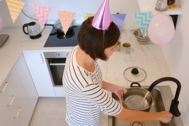 Genç bir kadın, rahat bir atmosfer ve şenlikli dekorasyonla çevrili olarak doğum gününü evde kutluyor. Şenlikli bir akşam yemeği pişiriyor, lezzetli bir makarna.