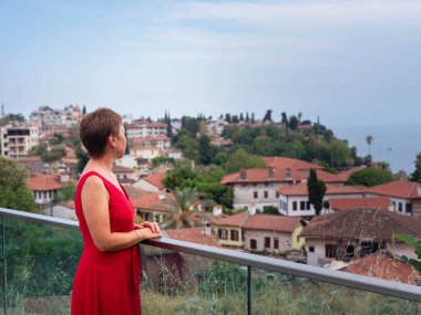 Sıcak yaz akşamları Antalya 'nın dar sokaklarında kırmızı elbiseli bir kadın yürüyor. Tarihsel atmosfer ve Akdeniz cazibesi barışçıl seyahat deneyimleri yaratır. Kalechi manzarası