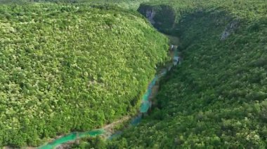 Korana nehri Plitvice yakınlarındaki yeşil tepelerden akar. Korana Nehri 'nin tepeler ve ormanlar boyunca kıvrımlı manzarası. Sıcak güneş ışığı ve Hırvat kırsalının zengin dokularına sahip taze bahar manzarası