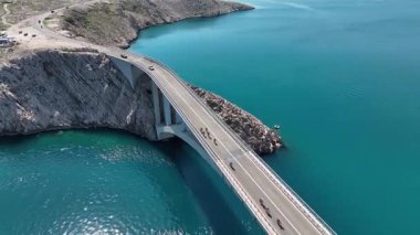 Mavi Adriyatik Denizi 'nin karşısındaki Köprü Pag Adası. Hırvatistan 'ı Pag Adası' na bağlayan köprü geniş çaplı insansız hava aracı görüntüsü. Çarpıcı deniz, kayalık kıyı şeridi, ılık bahar ışığı tonları dramatik bir kompozisyon oluşturur..