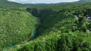 Korana nehri Plitvice yakınlarındaki yeşil tepelerden akar. Korana Nehri 'nin tepeler ve ormanlar boyunca kıvrımlı manzarası. Sıcak güneş ışığı ve Hırvat kırsalının zengin dokularına sahip taze bahar manzarası