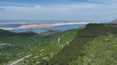 İlkbaharda Velebit dağ sırasından geçen manzara, bahar güneşinde yeşil Velebit dağlarından geçen yol, Hırvatların doğal manzarasını ve huzurlu uzak arazisini gösteriyor