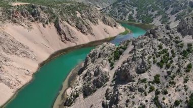 Obrovac 'tan nehir ağzı antenine kadar Zrmanja kanyonu nehri. Dolambaçlı Zrmanja nehrinin havadan çekimleri derin kanyonu, bereketli bahar renklerini ve uzak yolları kesiyor.