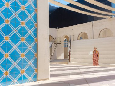 Abu Dabi 'de Qasr Al Hosn Parkı' nı keşfeden genç bir kadın. Yeşillik ve tarihi simgelerle çevrelenmiş, kentin kalbindeki sakin atmosfer ve Emirati mirasının tadını çıkarıyor..