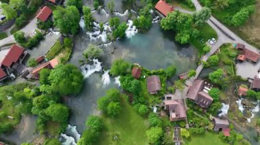 Slunj ve Korana nehirlerindeki Rastoke su değirmeni köyü. Şelaleleri, ahşap evleri, nehirleri akan sevimli Rastoke köyü. Hırvatistan 'ın göbeğindeki peri masalı bahar mevkiinin havadan görünüşü