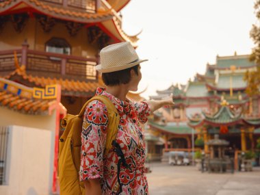 Bangkok 'taki Budist Tapınakları' nın yakınlarındaki Renkli Sokakları Keşfeden Kadın. Bangkok 'un canlı sokaklarında yürüyen genç bir gezgin, karmaşık tapınak detaylarına ve canlı çevresine hayran...