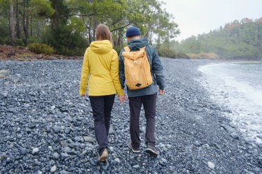 Çiftler Türk kıyı şeridini seviyor. Taşlarda oturmak, deniz dalgalarını izlemek, birlikte dinlenmek, sakin mavi suyun yanında, yumuşak kış ışığı altında romantik bir an..