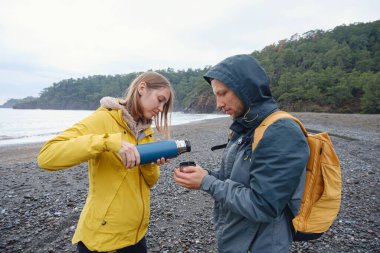 Çiftler Türk kıyı şeridini seviyor. Taşlarda oturmak, deniz dalgalarını izlemek, birlikte dinlenmek, sakin mavi suyun yanında, yumuşak kış ışığı altında romantik bir an..