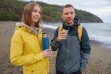 Çiftler Türk kıyı şeridini seviyor. Taşlarda oturmak, deniz dalgalarını izlemek, birlikte dinlenmek, sakin mavi suyun yanında, yumuşak kış ışığı altında romantik bir an..